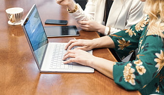 Two women typing on laptop during business meeting