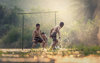 Boys playing football in muddy water field