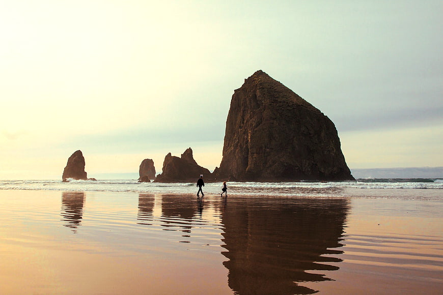 Silhouetted Couple Walking on Beach with Rock Formations