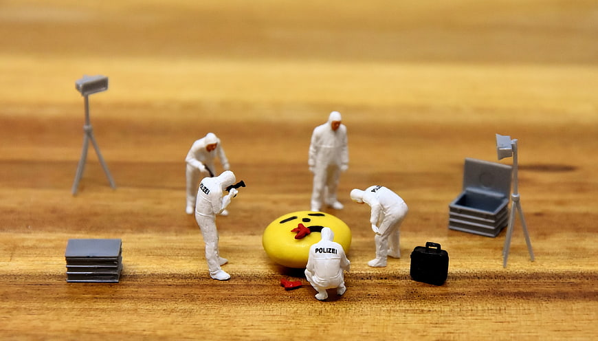 Miniature police forensic team investigating emoji crime scene