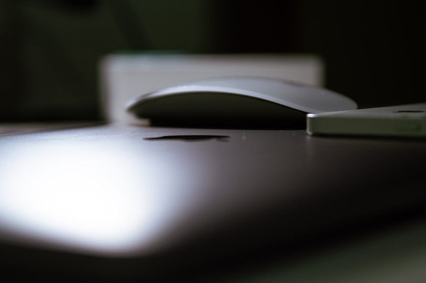 Close-up of Apple MacBook, Mouse, and iPhone on Desk