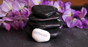 Stacked black zen stones with white trust stone and purple flowers