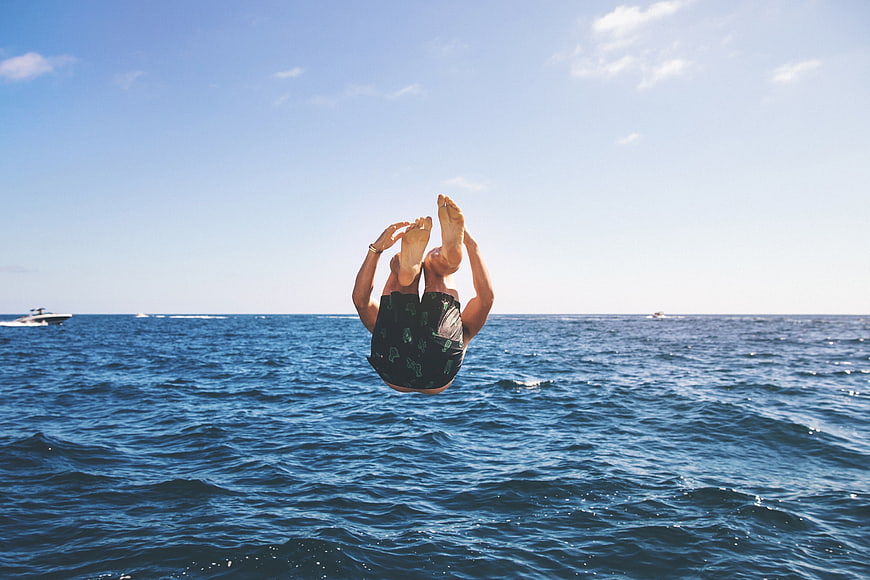 Man diving into ocean from boat in summer