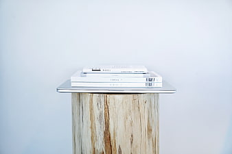 Minimalist stack of white books on rustic wooden stump