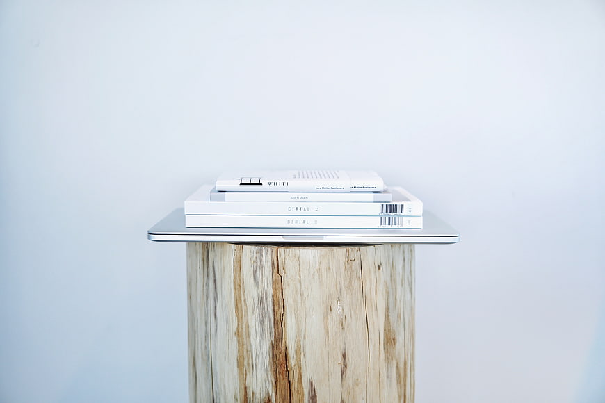 Minimalist stack of white books on rustic wooden stump