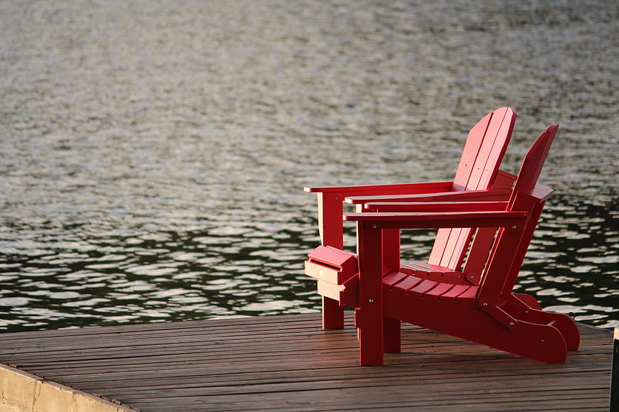 Red Adirondack Chairs on Wooden Dock by Lake