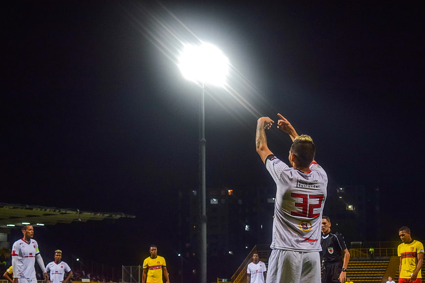 Soccer player celebrating goal under stadium floodlights at night