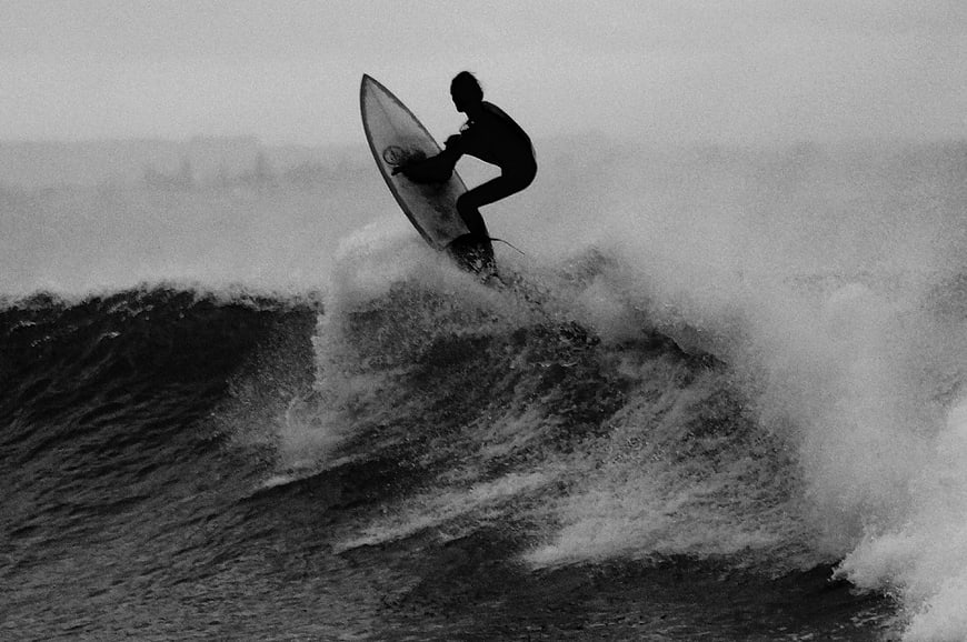 Silhouette of Surfer Riding Wave in Black and White