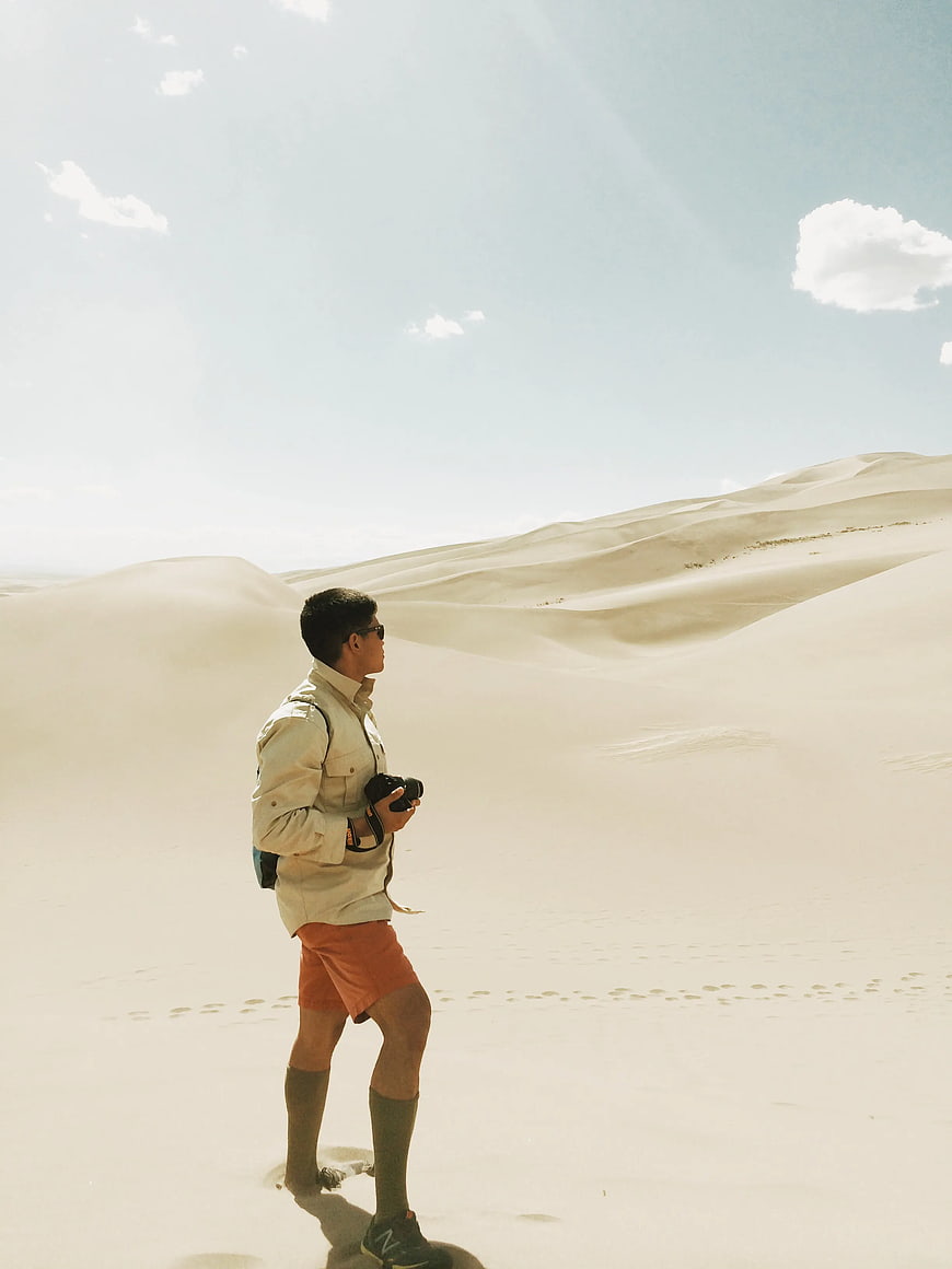 Man with Camera Standing in Sand Dunes