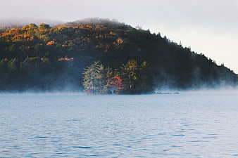 Misty Autumn Lake with Forested Hill and Fog