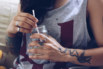 Close-up of tattooed woman holding glass jar with straw