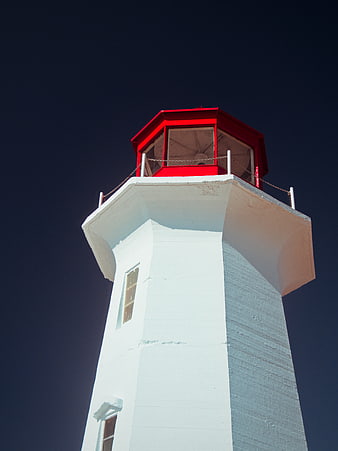 White Lighthouse with Red Lantern Room Against Dark Blue Sky