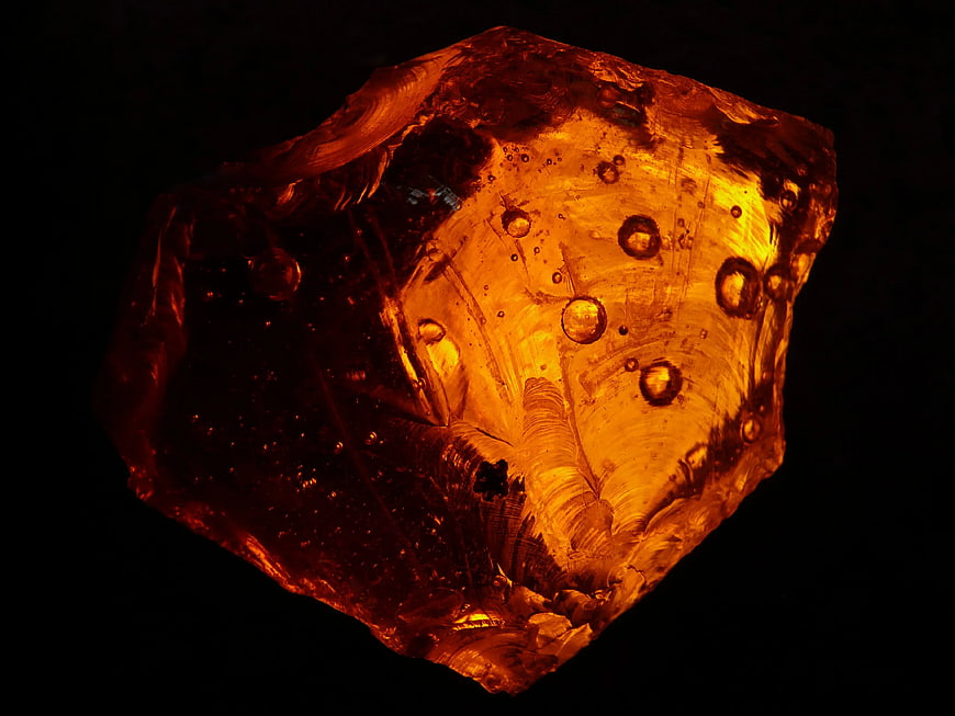 Glowing Amber Stone with Inclusions on Black Background