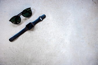 Black smartwatch and sunglasses on textured concrete background