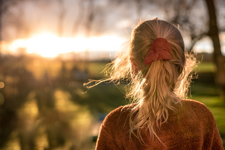 Woman with blonde ponytail watching sunset in park