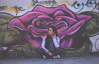 Young Woman Sitting in Front of Colorful Graffiti Mural