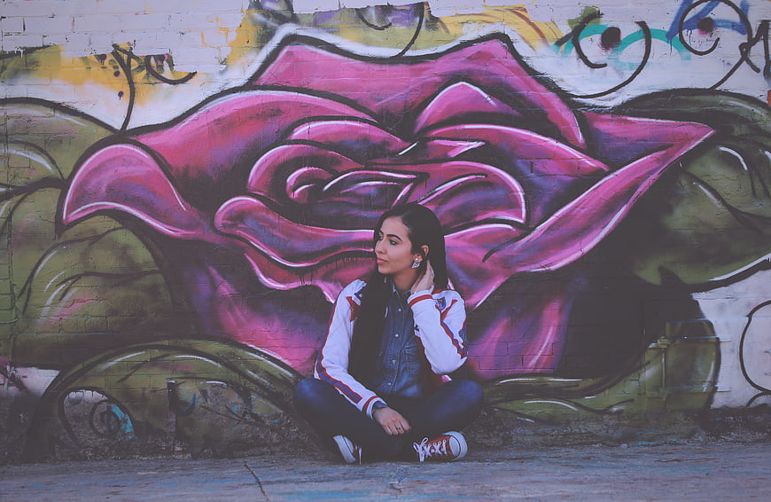 Young Woman Sitting in Front of Colorful Graffiti Mural
