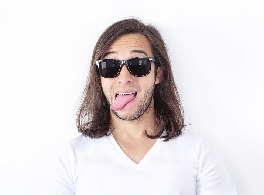 Funny man with long hair sticking tongue out wearing sunglasses