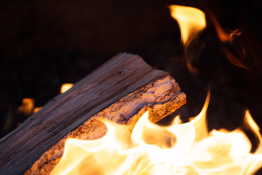 Close-up of burning wood log with bright orange flames