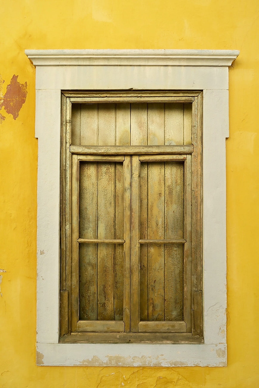 Old wooden window on yellow wall