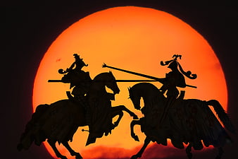 Silhouette of Two Medieval Knights Jousting Against a Giant Orange Sun