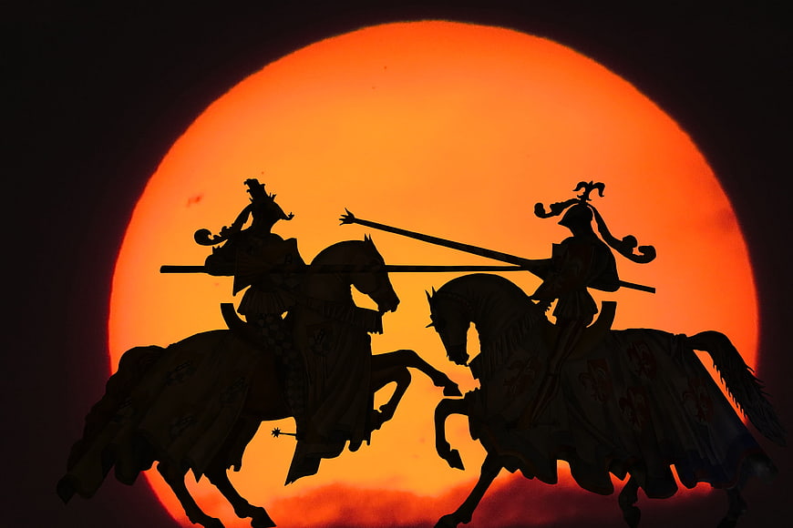 Silhouette of Two Medieval Knights Jousting Against a Giant Orange Sun