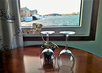 Upside-down wine glasses and orchid on table with harbor view