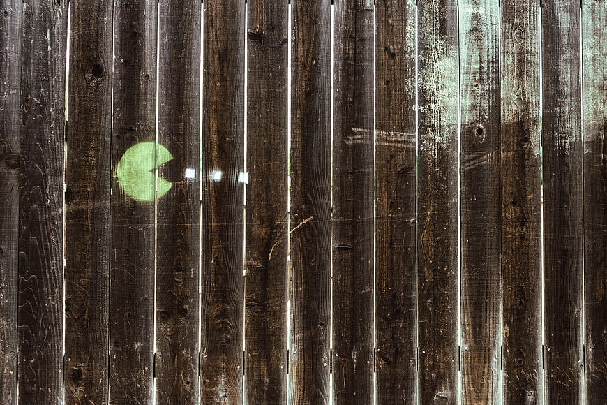 Pac-Man graffiti on weathered wooden fence planks