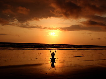 Silhouette of Woman Meditating on Beach at Sunset