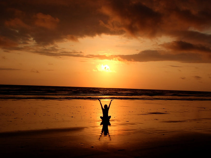 Silhouette of Woman Meditating on Beach at Sunset