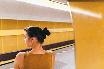 Woman in yellow top waiting at yellow subway station