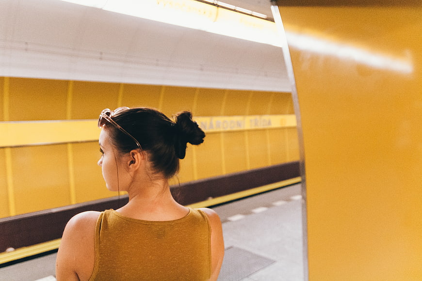 Woman in yellow top waiting at yellow subway station
