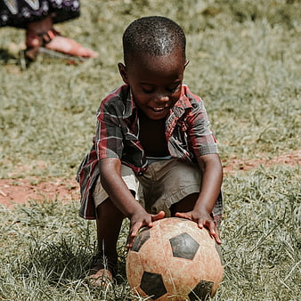 Happy African Child Playing with Soccer Ball on Grass