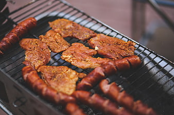 Seasoned pork steaks and sausages grilling on barbecue