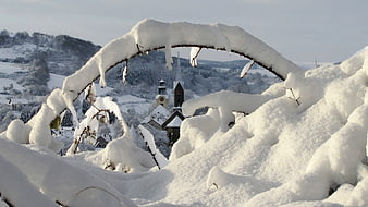 Snow-covered church framed by icy branches in winter landscape