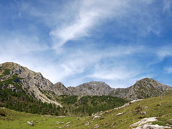 Scenic Alpine Mountain Landscape with Green Meadow and Blue Sky