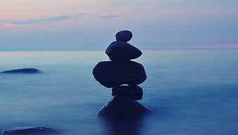 Stacked stones on calm lake water at dusk