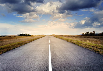 Empty asphalt road stretching to horizon under dramatic cloudy sky