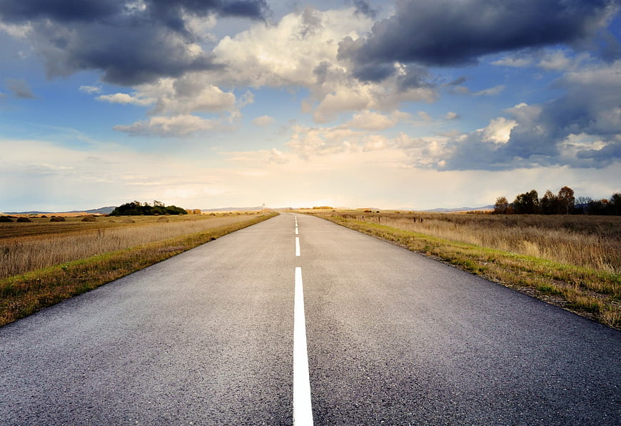 Empty asphalt road stretching to horizon under dramatic cloudy sky