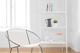 Minimalist white interior with rattan chair and bookshelf