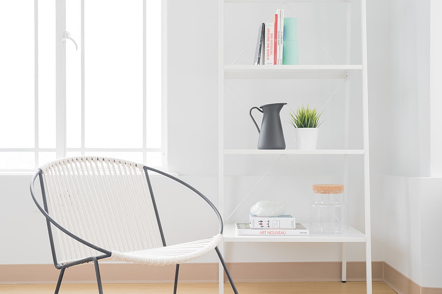 Minimalist white interior with rattan chair and bookshelf
