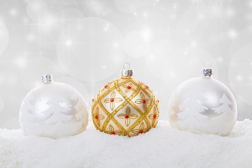 White and Gold Christmas Ornaments on Snow with Sparkling Background