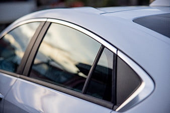 Close-up of white car window with chrome trim and reflection