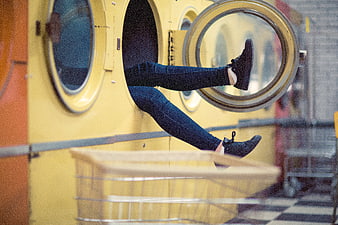 Woman's legs sticking out of yellow washing machine