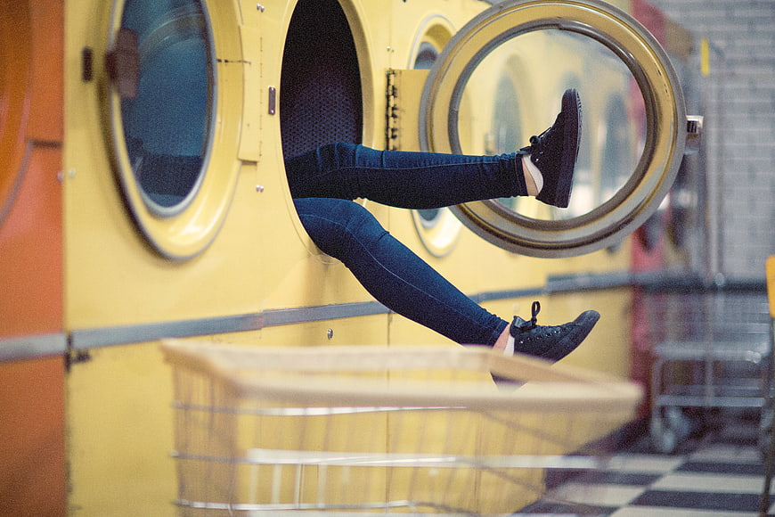 Woman's legs sticking out of yellow washing machine