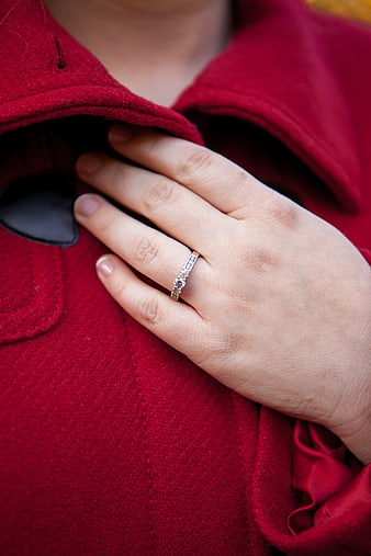Close-up of diamond engagement ring on hand in red coat