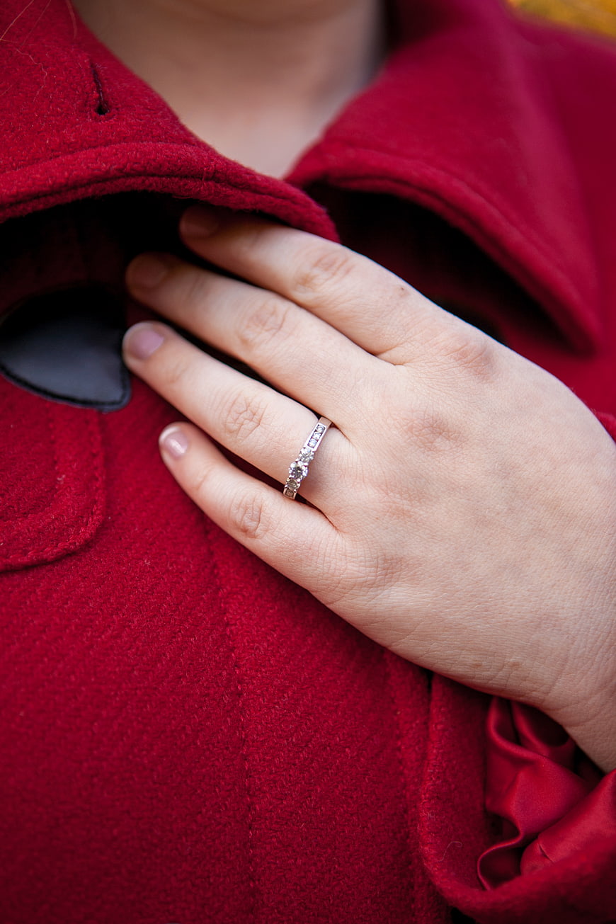 Close-up of diamond engagement ring on hand in red coat