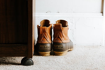 Brown leather boots on carpet near wooden furniture