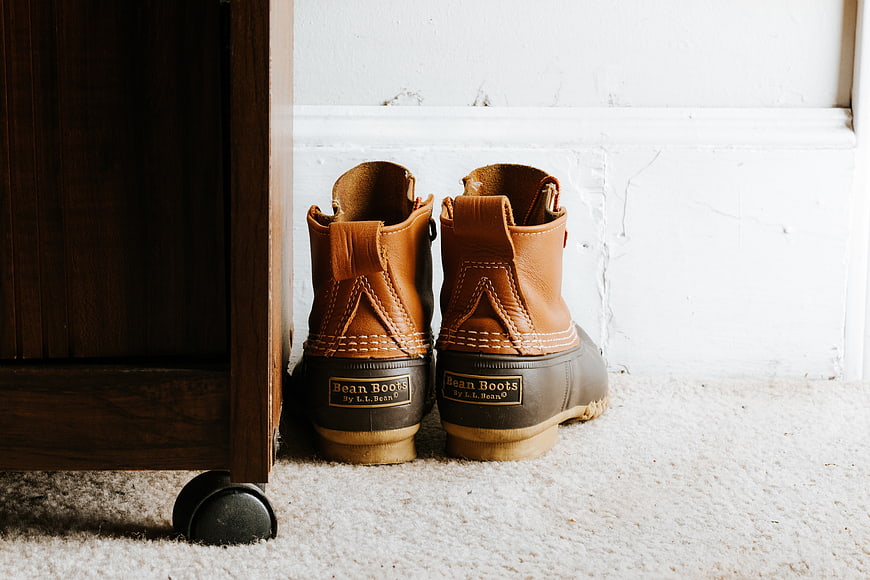 Brown leather boots on carpet near wooden furniture