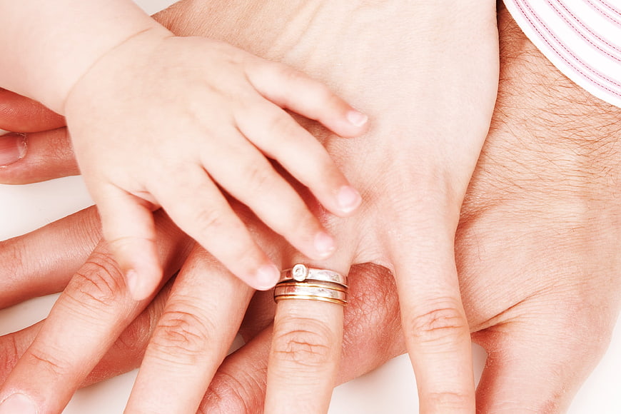 Family hands stacked together with wedding rings